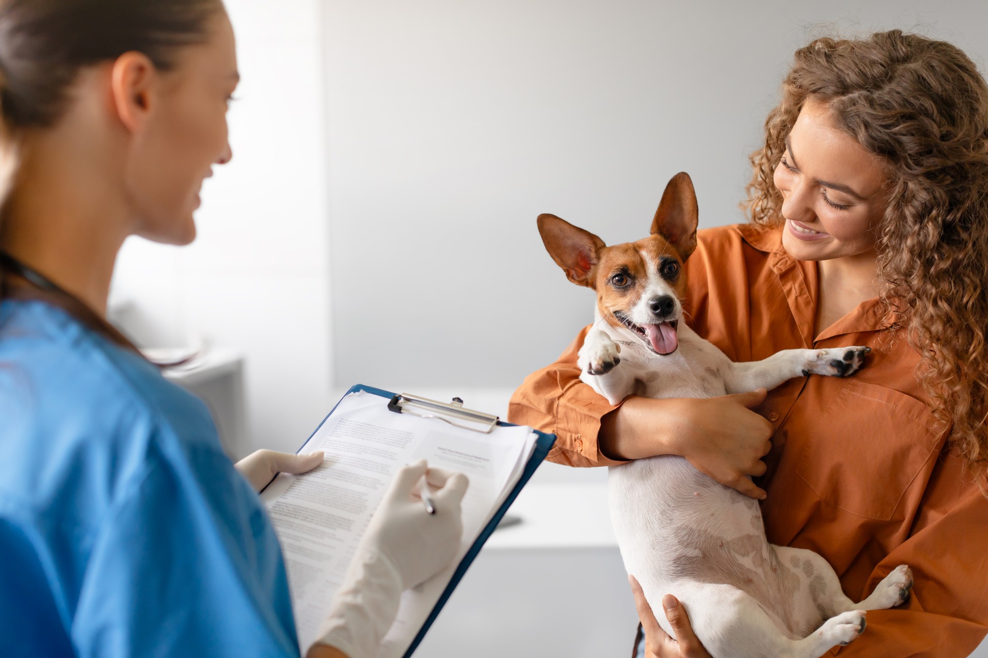 Vet with chart; woman holds happy dog